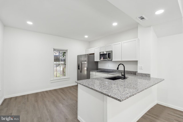 707 S Braddock St, Winchester, VA 22601 - kitchen featuring appliances with stainless steel finishes, a sink, light wood finished floors, light stone countertops, and white cabinetry