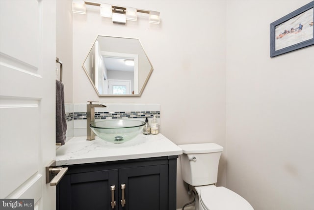 bathroom featuring vanity, decorative backsplash, and toilet