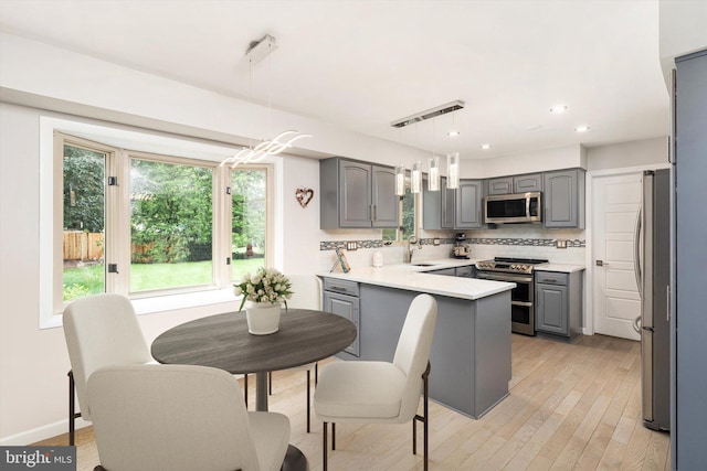 kitchen with stainless steel appliances, gray cabinets, a peninsula, a sink, and recessed lighting