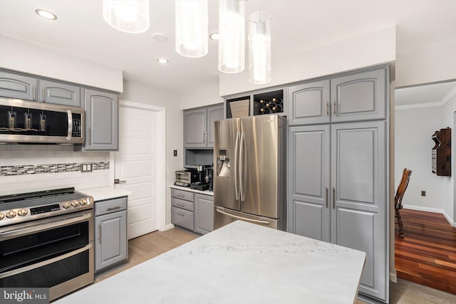 kitchen with gray cabinets, appliances with stainless steel finishes, light wood finished floors, tasteful backsplash, and recessed lighting