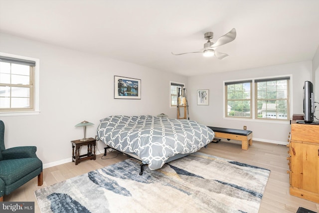 bedroom featuring multiple windows, light wood-style floors, baseboards, and a ceiling fan