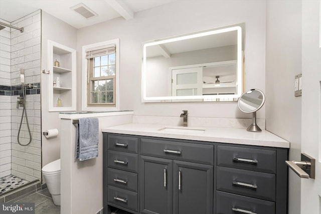 bathroom featuring vanity, a tile shower, toilet, a ceiling fan, and beamed ceiling