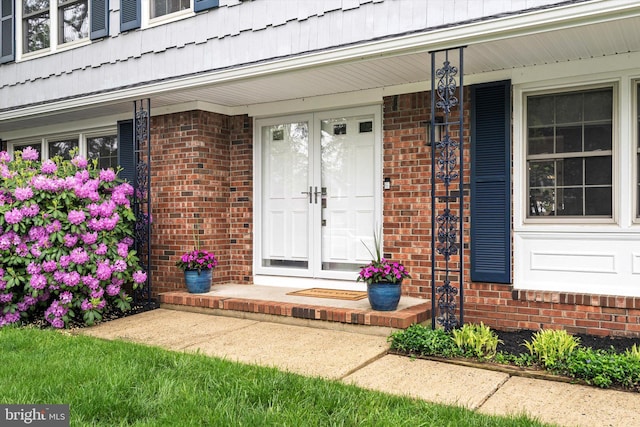 doorway to property with covered porch and brick siding