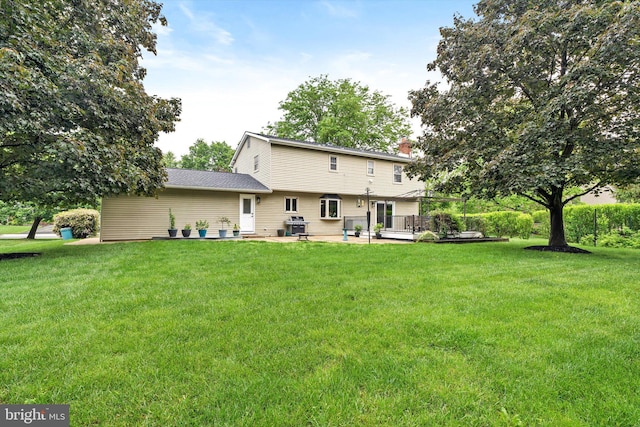 rear view of house with a yard, a chimney, and a patio