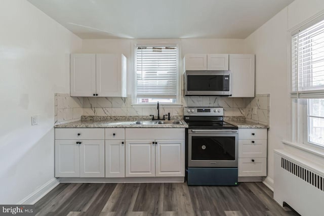 kitchen with stainless steel appliances, radiator, a sink, and dark wood-style floors
