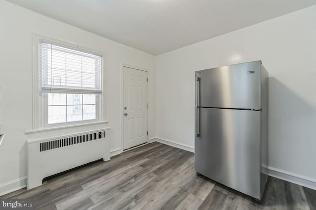 kitchen featuring freestanding refrigerator, radiator, wood finished floors, and baseboards