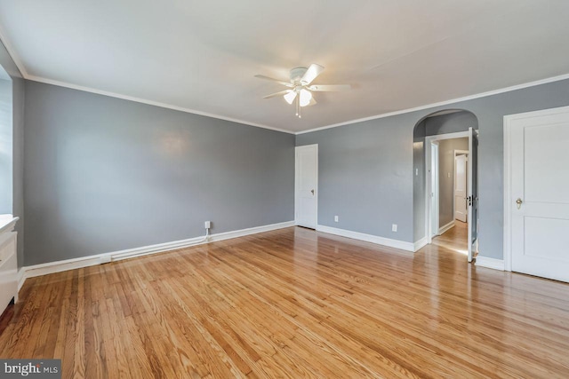empty room with ceiling fan, arched walkways, light wood-style flooring, baseboards, and ornamental molding