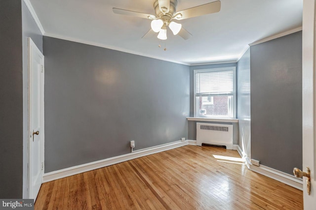 unfurnished room with radiator, ornamental molding, a ceiling fan, wood finished floors, and baseboards