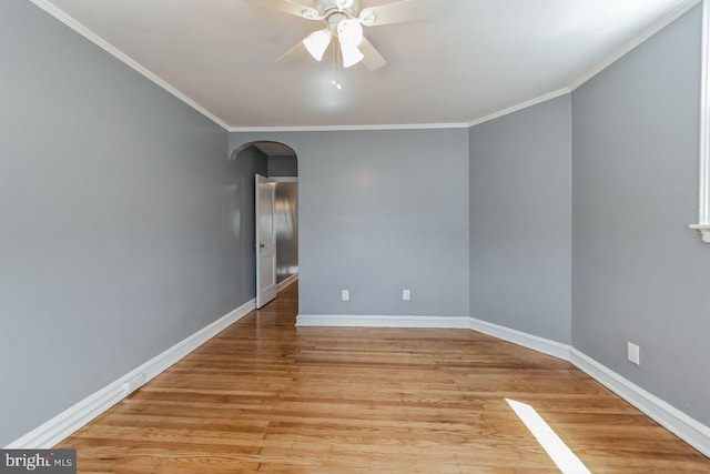 unfurnished room with arched walkways, light wood finished floors, crown molding, a ceiling fan, and baseboards
