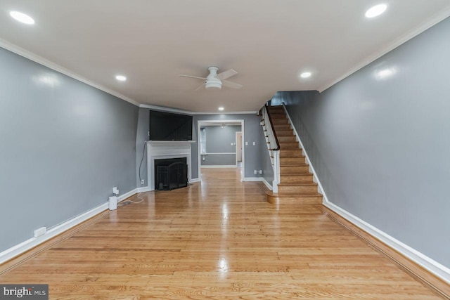 unfurnished living room featuring a ceiling fan, ornamental molding, a fireplace, stairway, and baseboards