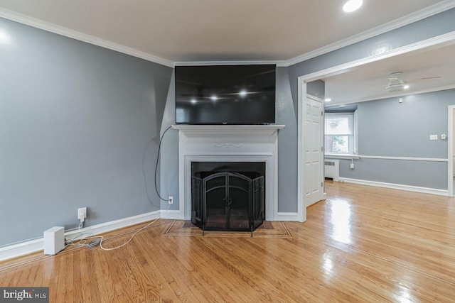 unfurnished living room with radiator, ornamental molding, wood finished floors, baseboards, and a fireplace with flush hearth