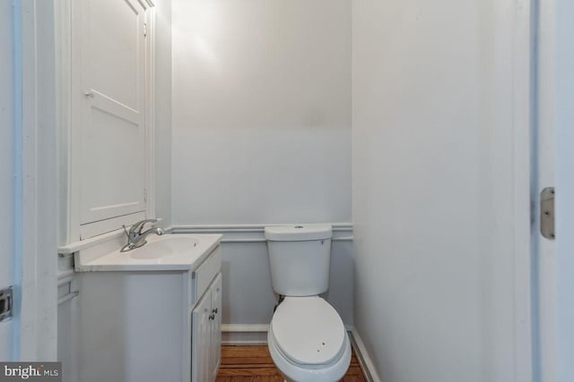 half bathroom featuring vanity, toilet, and baseboards
