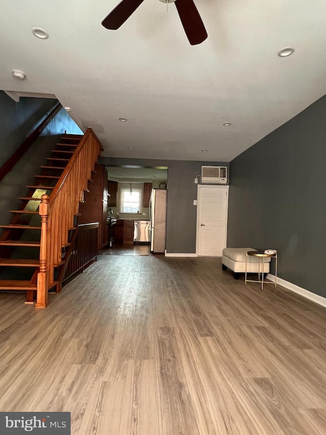 unfurnished living room featuring a ceiling fan, wood finished floors, stairway, baseboards, and recessed lighting