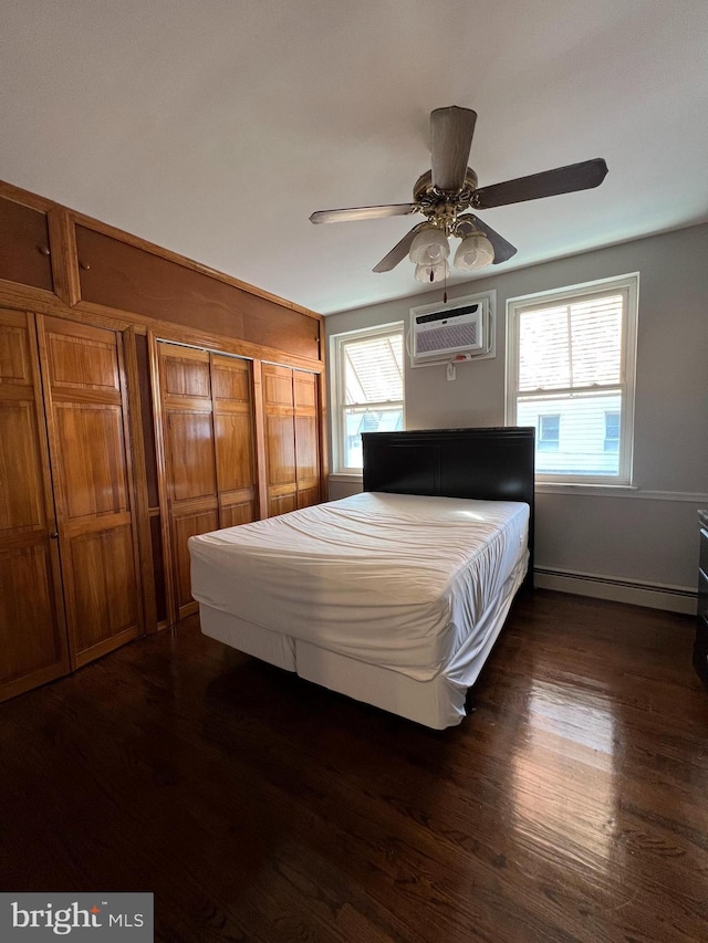 bedroom featuring baseboard heating, a wall mounted AC, dark wood-style floors, and multiple windows