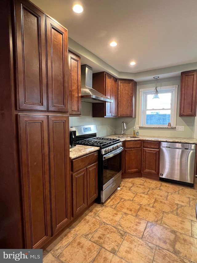 kitchen featuring appliances with stainless steel finishes, wall chimney exhaust hood, a sink, recessed lighting, and light stone countertops