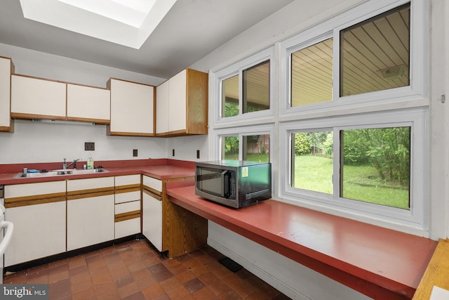 13111 Valleywood Dr, Silver Spring, MD 20906 - kitchen featuring stainless steel microwave, a sink, white cabinets, and a skylight