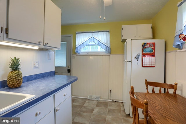 337 W Perry St, Enola, PA 17025 - kitchen with freestanding refrigerator, white cabinets, a sink, a wainscoted wall, and dark countertops