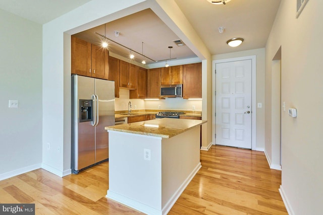 2200 N Westmoreland St Unit 325, Arlington, VA 22213 - kitchen with appliances with stainless steel finishes, light wood-type flooring, light stone counters, a center island, and brown cabinets