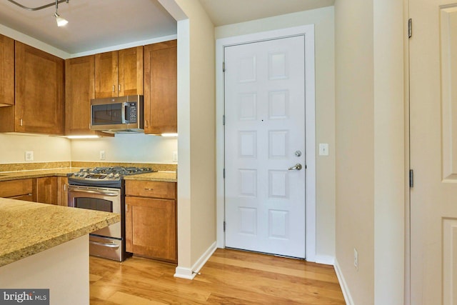 2200 N Westmoreland St Unit 325, Arlington, VA 22213 - kitchen with appliances with stainless steel finishes, light wood finished floors, brown cabinetry, and rail lighting