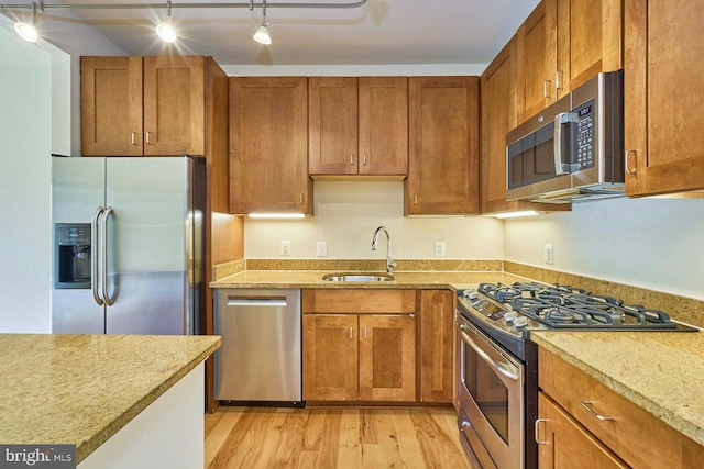 2200 N Westmoreland St Unit 325, Arlington, VA 22213 - kitchen featuring stainless steel appliances, light wood finished floors, brown cabinetry, and light stone counters