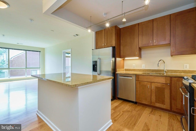 2200 N Westmoreland St Unit 325, Arlington, VA 22213 - kitchen featuring stainless steel appliances, light wood-type flooring, brown cabinetry, light stone counters, and a kitchen island