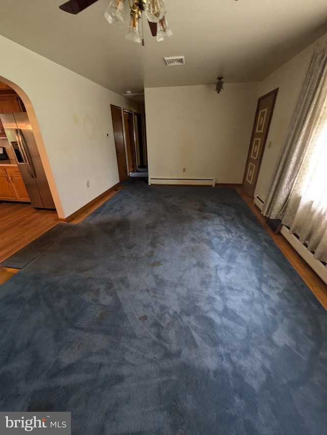 671 Woodview St, Steelton, PA 17113 - unfurnished living room with a baseboard heating unit, arched walkways, a ceiling fan, baseboards, and dark carpet