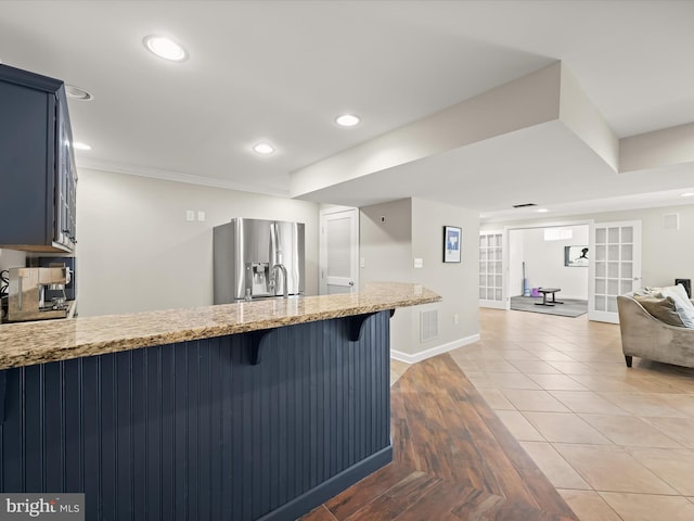 720 Cyprian Ct, Gambrills, MD 21054 - kitchen with stainless steel refrigerator with ice dispenser, a peninsula, light stone countertops, a breakfast bar area, and baseboards