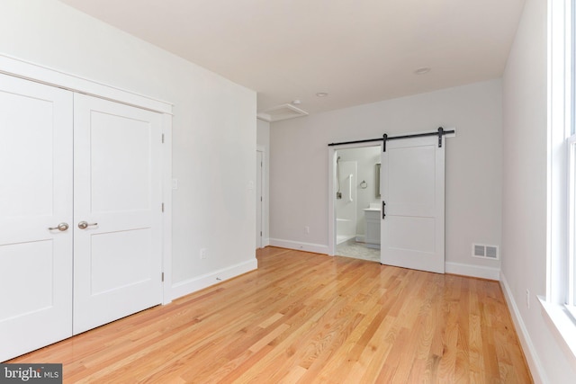 134 Stony Pointe Way, Strasburg, VA 22657 - unfurnished bedroom with wood finished floors, a barn door, baseboards, and ensuite bathroom