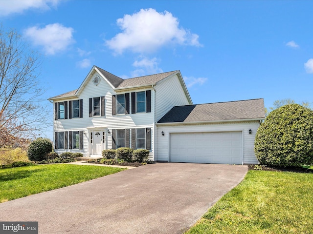 colonial inspired home with concrete driveway, an attached garage, and a front yard