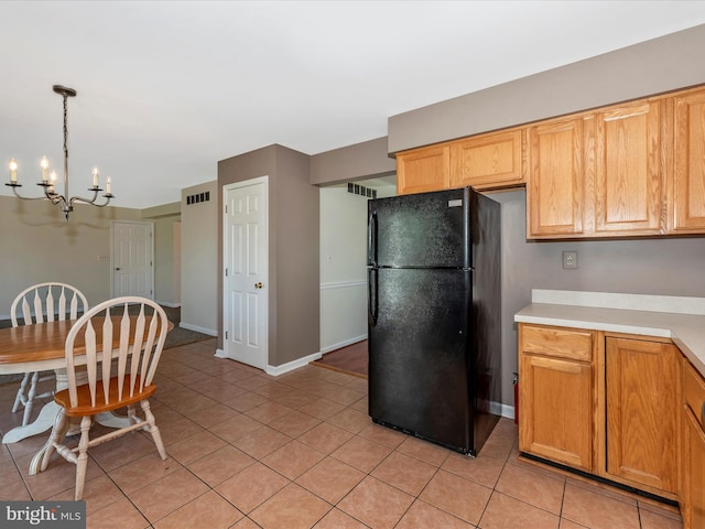kitchen featuring freestanding refrigerator, a chandelier, light tile patterned flooring, light countertops, and decorative light fixtures