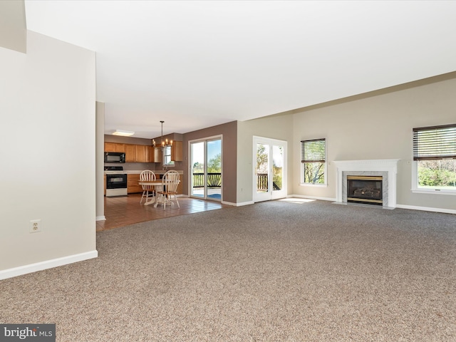 unfurnished living room with dark carpet, baseboards, healthy amount of natural light, and a premium fireplace