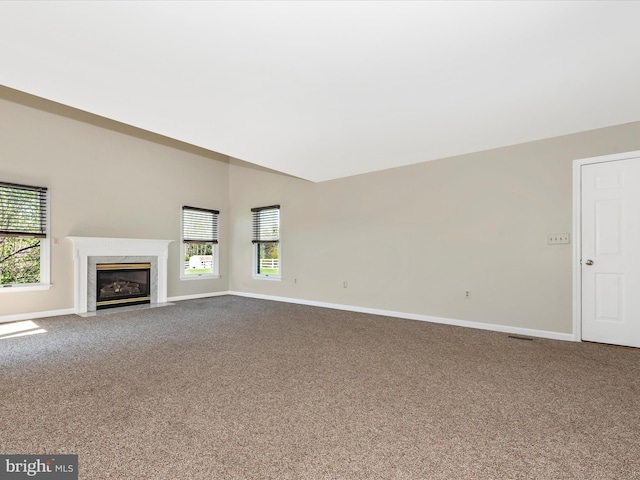 unfurnished living room featuring baseboards, carpet, and a high end fireplace