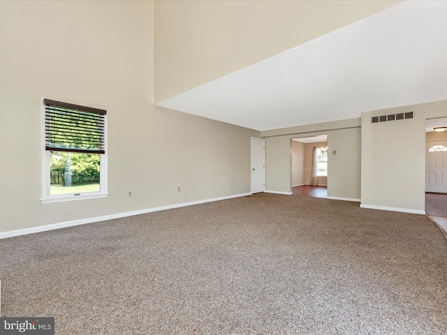 carpeted empty room with baseboards and a high ceiling