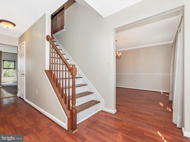 stairs featuring a chandelier, wood finished floors, and baseboards