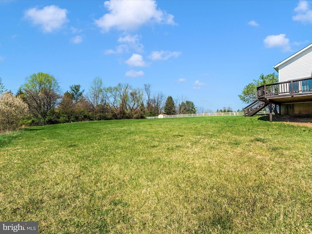 view of green lawn with a deck, stairs, and a view of countryside