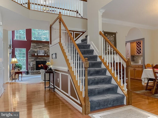 9150 Sparkling Pl, Charlotte Hall, MD 20622 - stairway featuring wood finished floors, ornamental molding, a fireplace, and a high ceiling