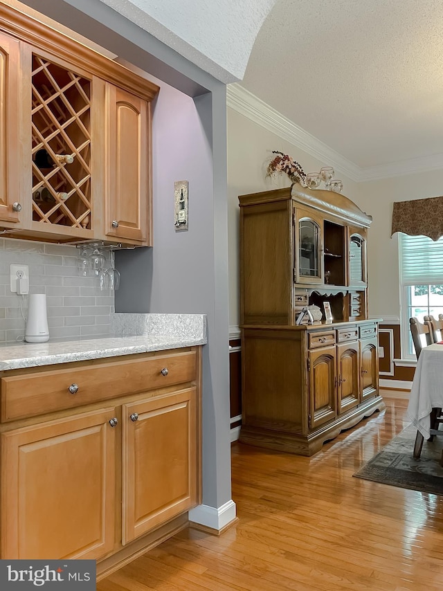 9150 Sparkling Pl, Charlotte Hall, MD 20622 - indoor dry bar with light wood-style flooring, backsplash, ornamental molding, a textured ceiling, and baseboards