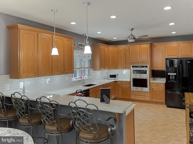 9150 Sparkling Pl, Charlotte Hall, MD 20622 - kitchen featuring appliances with stainless steel finishes, a sink, a kitchen bar, decorative light fixtures, and a peninsula