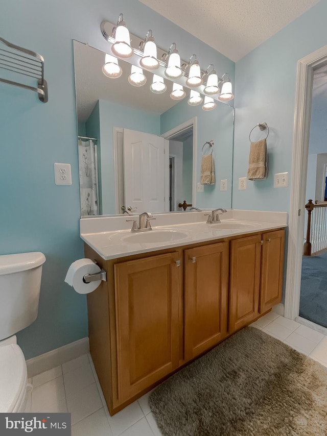9150 Sparkling Pl, Charlotte Hall, MD 20622 - bathroom featuring toilet, double vanity, tile patterned floors, and a textured ceiling
