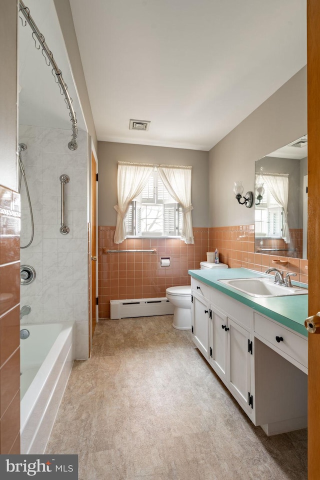 904 W Main St, New Holland, PA 17557 - full bathroom with a baseboard heating unit, tile walls, plenty of natural light, vanity, and toilet