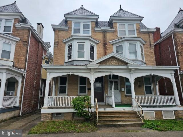 victorian-style house featuring covered porch and brick siding