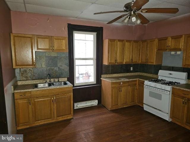 kitchen featuring gas range gas stove, a sink, a baseboard heating unit, and tasteful backsplash