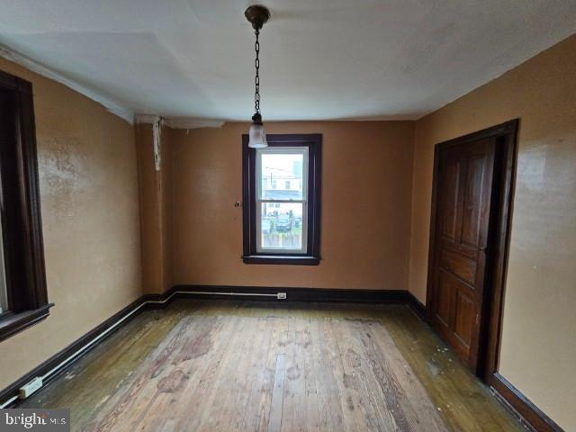 empty room featuring wood-type flooring and baseboards