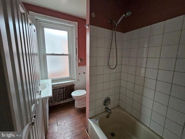 full bathroom featuring radiator, plenty of natural light, toilet, wood finished floors, and wainscoting
