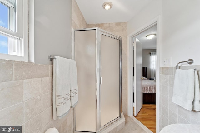 bathroom featuring tile walls, a shower stall, ensuite bath, and wainscoting