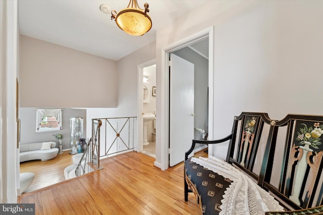 hallway featuring an upstairs landing, wood finished floors, and baseboards