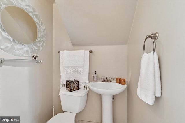half bath featuring vaulted ceiling and toilet