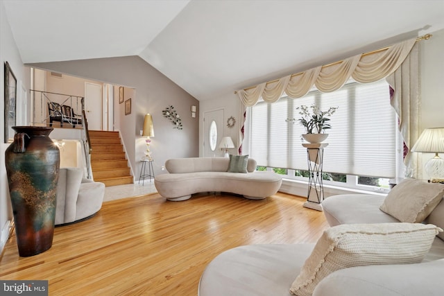living room featuring stairs, wood finished floors, and vaulted ceiling