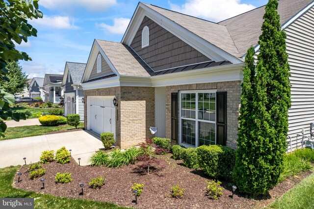 21 Whaleback Ln, Fredericksburg, VA 22406 - view of side of home with brick siding, driveway, a garage, a standing seam roof, and roof with shingles