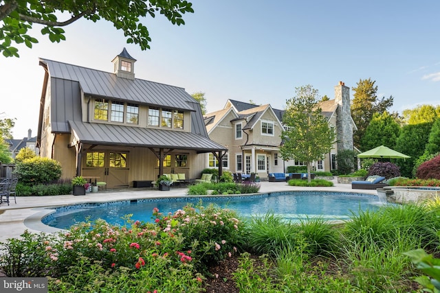 6529 Sothoron Rd, Mclean, VA 22101 - rear view of house featuring a standing seam roof, outdoor lounge area, a patio area, and an outdoor pool
